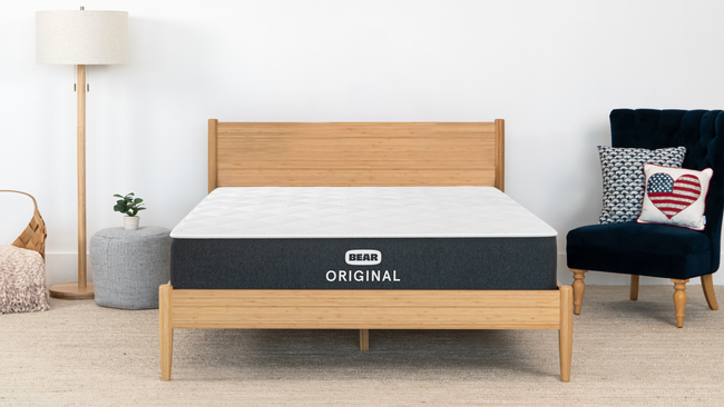 Bear Original mattress on natural wood bed frame in bright modern bedroom with bamboo accents for The Mattress Shop, showcasing product image Bear Original on the page: Best Memory Foam Mattresses page.