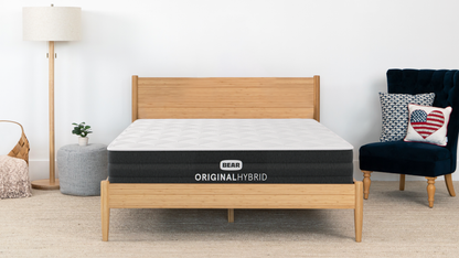 Bear Original Hybrid mattress on bamboo bed frame in bright modern bedroom with floor lamp and navy chair