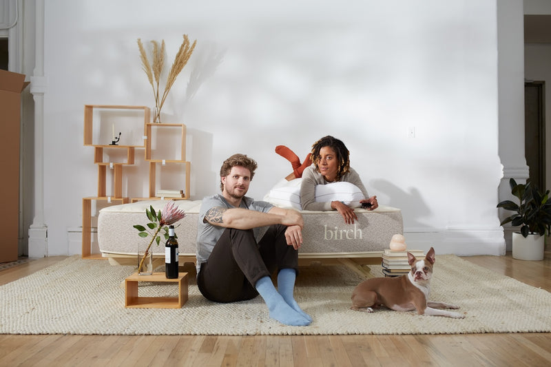 Two people and a dog sitting on the Birch Natural Mattress