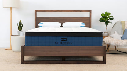 Bear Elite Ultra Hybrid Mattress in navy and white on a walnut bed frame in a bright modern bedroom