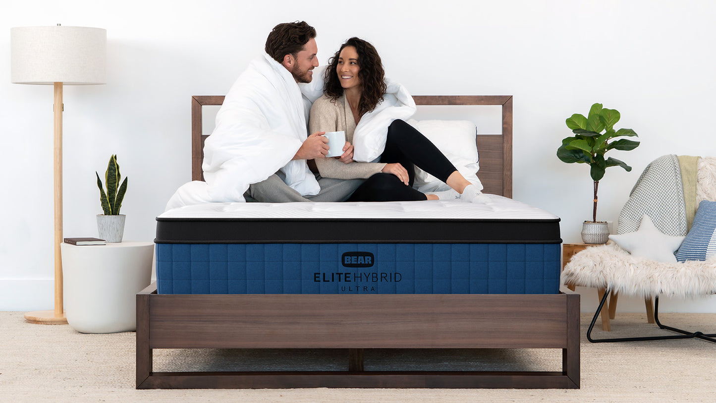 Couple relaxing together on Bear Elite Ultra HybridMattress, showcasing motion isolation and comfort for The Mattress Shop, showcasing product image for Bear Elite Ultra Hybrid on the product page.