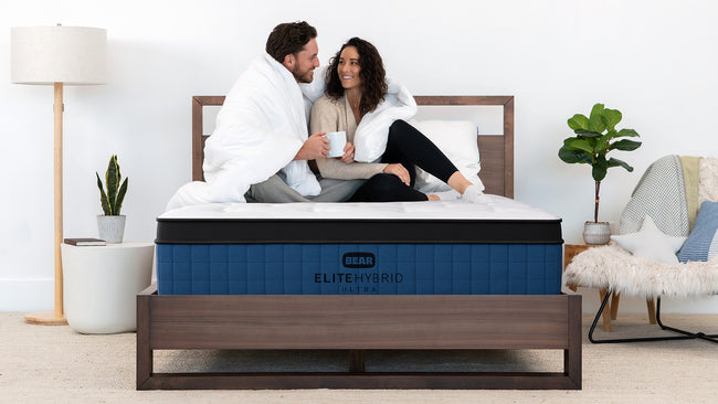 Couple relaxing together on Bear Elite Ultra HybridMattress, showcasing motion isolation and comfort for The Mattress Shop, showcasing product thumbnail image for Bear Elite Ultra Hybrid on the product page.