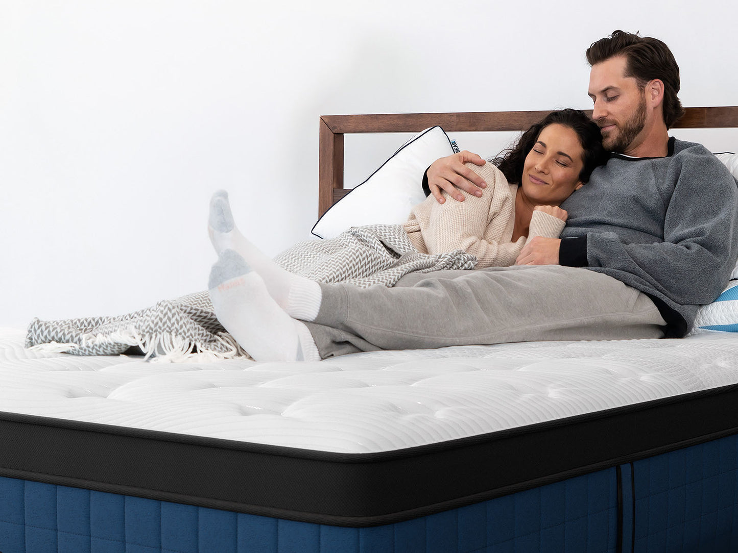 Couple relaxing together on Bear Elite Ultra Hybrid Mattress, showcasing motion isolation and comfort for The Mattress Shop, showcasing product image for Bear Elite Ultra Hybrid on the product page.