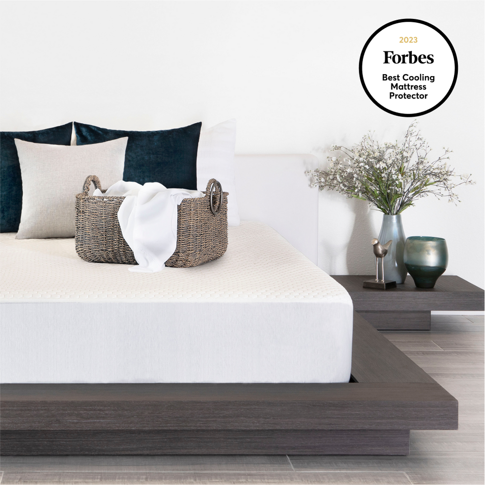 Bedroom scene with a bed featuring a cooling mattress protector, pillows, and decorative items