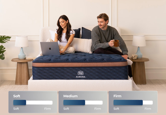Brooklyn Bedding Aurora mattress available in soft, medium, and firm, couple sitting on bed with laptop and coffee. for The Mattress Shop, showcasing product image Brooklyn Bedding Aurora Luxe Cooling on the page: Best Hybrid Mattresses page.