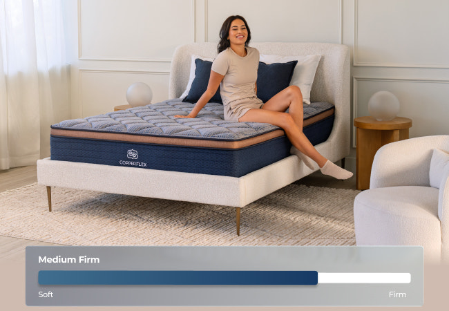 Brooklyn Bedding CopperFlex medium firm mattress, firmness scale soft to firm, woman sitting on bed for The Mattress Shop, showcasing product image Brooklyn Bedding CopperFlex® on the page: Best Hybrid Mattresses - Quiz Prominent CTA page.