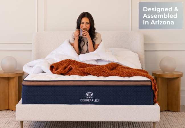 Brooklyn Bedding CopperFlex Pro mattress, woman sitting up in bed with blanket, designed and assembled in Arizona for The Mattress Shop, showcasing product image Brooklyn Bedding CopperFlex® Pro on the page: Best Hybrid Mattresses page.