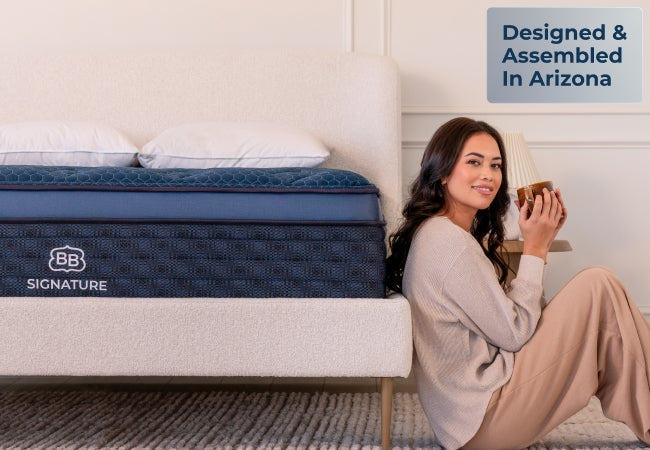 Brooklyn Bedding Signature mattress with woman sitting against bed holding mug, designed and assembled in Arizona. for The Mattress Shop, showcasing product thumbnail image for Brooklyn Bedding Signature Hybrid on the product page.