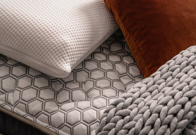 Brooklyn Bedding Titan Plus Elite mattress close-up showing hexagon quilted pillow top with pillows and cozy blanket for The Mattress Shop, showcasing product thumbnail image for Brooklyn Bedding Titan® Plus Elite on the product page.