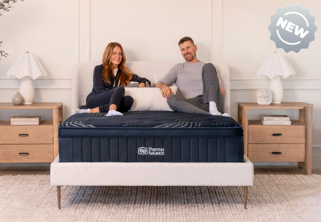 Brooklyn Bedding ThermoBalance mattress new design, couple sitting together on navy blue pillow top. for The Mattress Shop, showcasing product thumbnail image for Brooklyn Bedding ThermoBalance on the product page.
