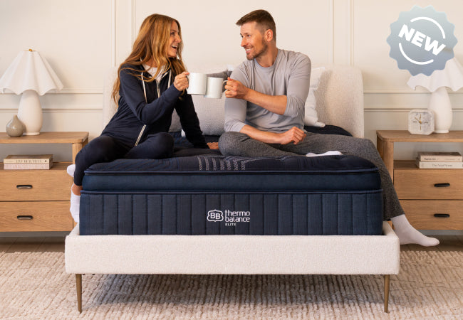Brooklyn Bedding ThermoBalance Elite new mattress, couple sitting on bed toasting mugs together. for The Mattress Shop, showcasing product image for Brooklyn Bedding ThermoBalance Elite on the product page.