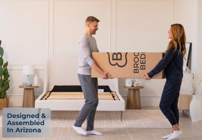 Brooklyn Bedding ThermoBalance LX mattress in box carried by couple, designed and assembled in Arizona for The Mattress Shop, showcasing product image for Brooklyn Bedding ThermoBalance LX on the product page.