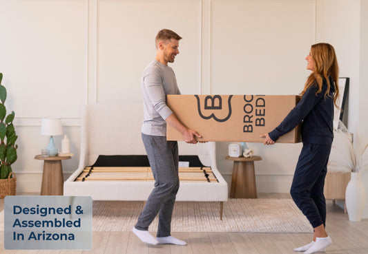 Brooklyn Bedding ThermoBalance LX mattress in box carried by couple, designed and assembled in Arizona for The Mattress Shop, showcasing product image for Brooklyn Bedding ThermoBalance LX on the collection page.