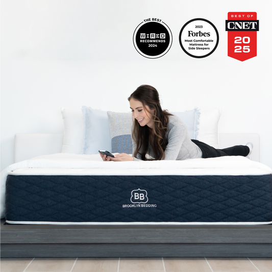 Woman lying on brooklyn bedding signature mattress smiling on her phone in a bedroom scene