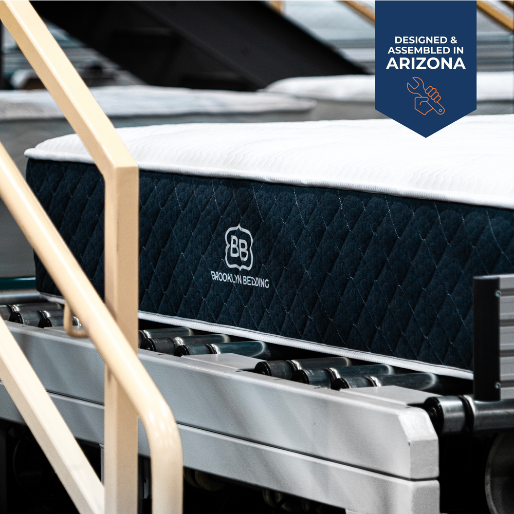 Brooklyn Bedding signature mattress in mattress factory assembly line with 'Designed & Assembled in Arizona' badge.