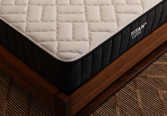 Brooklyn Bedding Titan+ Core mattress corner detail showing quilted top and side panel stitching on wood frame. for The Mattress Shop, showcasing product image for Brooklyn Bedding Titan Plus Core on the product page.