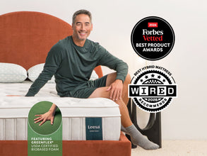 Man relaxing on Leesa Sapira Chill mattress with orange headboard, earning Forbes Vetted and Wired award badges. for The Mattress Shop, showcasing product image Leesa Sapira Chill Hybrid Mattress on the page: Sale Landing page.
