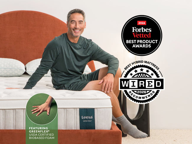 Man relaxing on Leesa Sapira Chill mattress with orange headboard, earning Forbes Vetted and Wired award badges. for The Mattress Shop, showcasing product thumbnail image for Leesa Sapira Chill Hybrid Mattress on the product page.