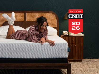 Woman laughing on Leesa Legend Hybrid mattress with rattan headboard, named Best of CNET 2026.