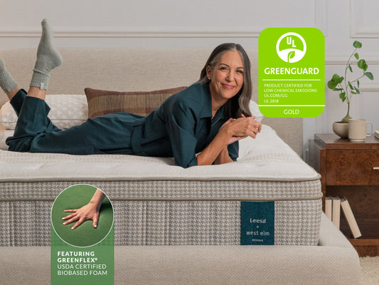 Woman smiling on Leesa Legend Hybrid mattress with rattan headboard, Greenguard certified for The Mattress Shop, showcasing product image for Leesa Reserve Hybrid Mattress on the page: About Leesa page.